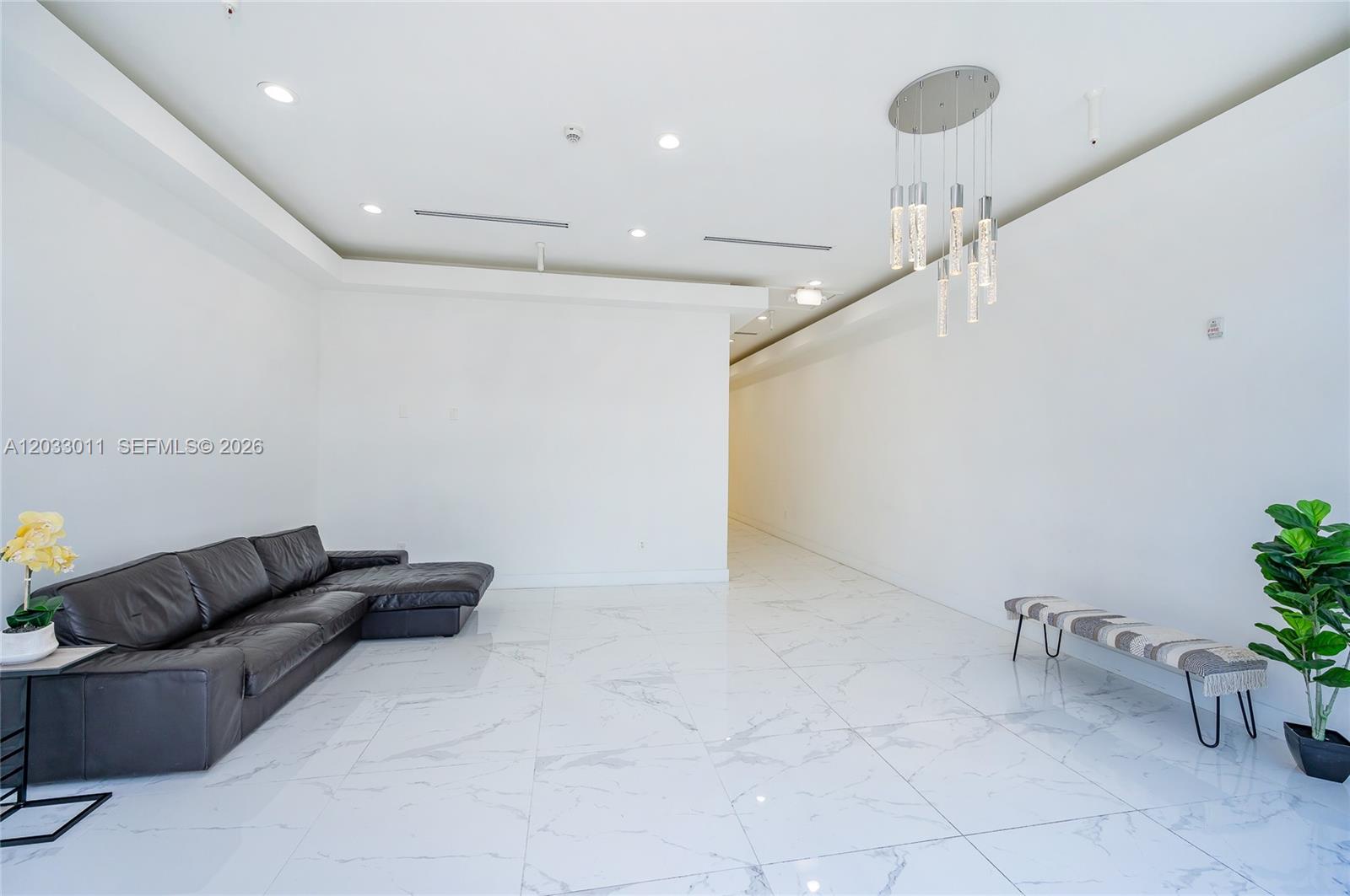 A minimalist room features white walls, marble-patterned tile floors, a black sectional, and pendant lighting — 10450 NW 33rd St # 301, Doral FL 33172, DORAL, FL