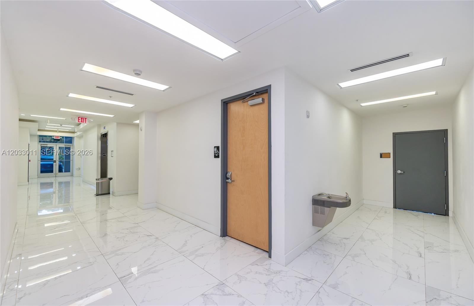 A bright hallway features white marble-look tile flooring, recessed lighting, and two closed doors — 10450 NW 33rd St # 301, Doral FL 33172, DORAL, FL