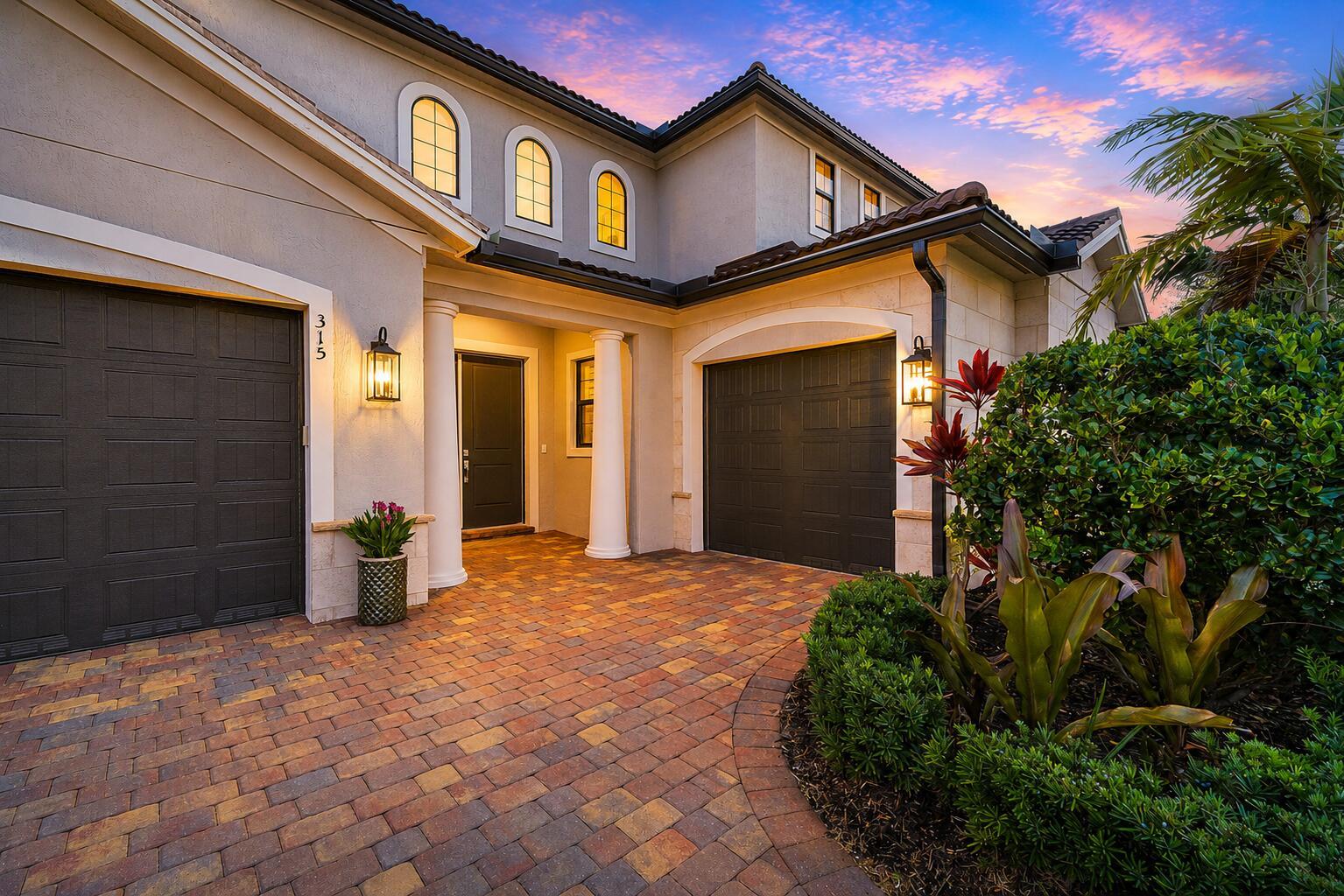 A two-story house exterior features a paved driveway, two garage doors, and a covered entryway — 315 Sonoma Isles Circle, Jupiter FL 33478, JUPITER, FL