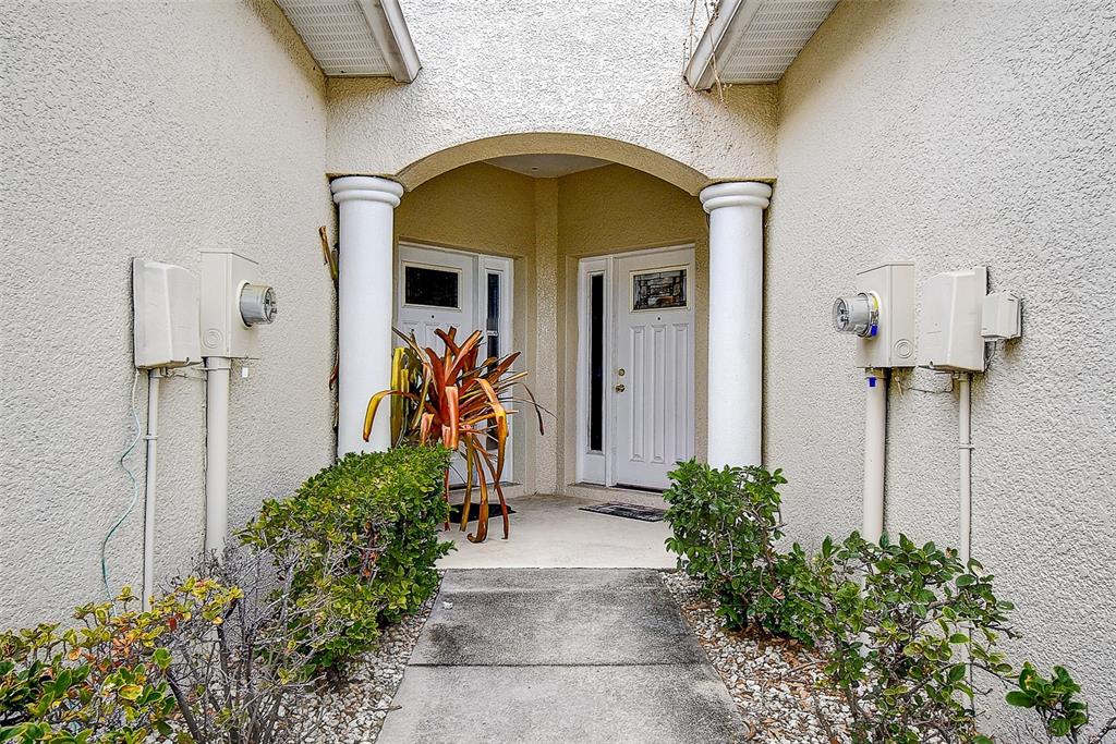 An exterior view of a duplex entrance with two white doors, columns, and utility meters — 14985 ALAN COURT, LARGO, FL