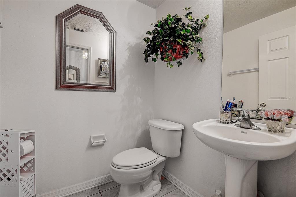 A bathroom features a pedestal sink, a toilet, a wall mirror, and a hanging plant — 14985 ALAN COURT, LARGO, FL