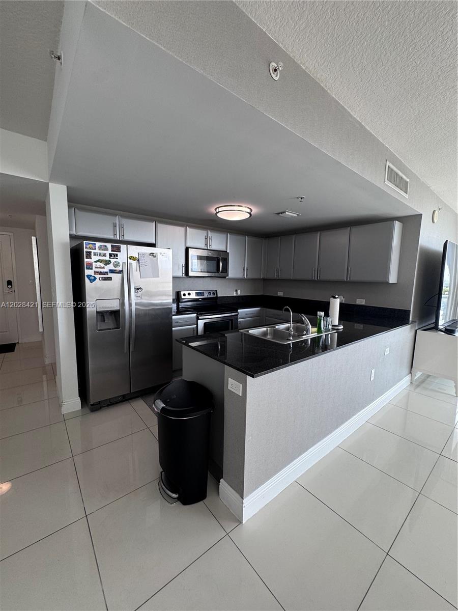 A kitchen features stainless steel appliances, dark granite countertops, and light gray cabinetry — 1861 NW S River Dr # 906, Miami FL 33125, MIAMI, FL