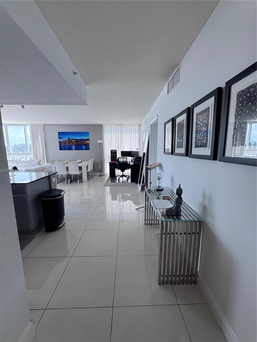 A bright, open-concept living area features white tile flooring, a dining set, and a workspace — 1861 NW S River Dr # 906, Miami FL 33125, MIAMI, FL