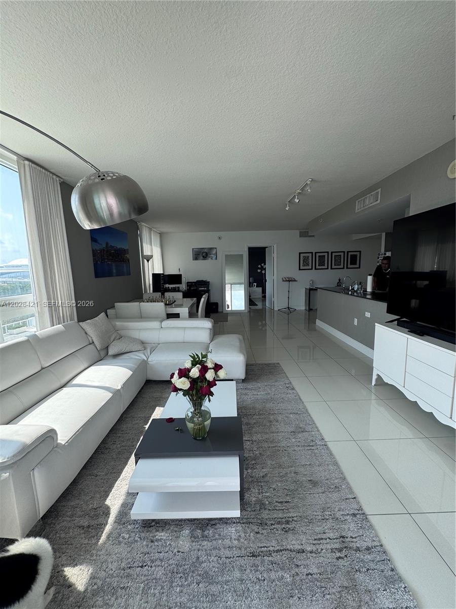 A modern living room features a white sectional sofa, a coffee table, and tile flooring — 1861 NW S River Dr # 906, Miami FL 33125, MIAMI, FL