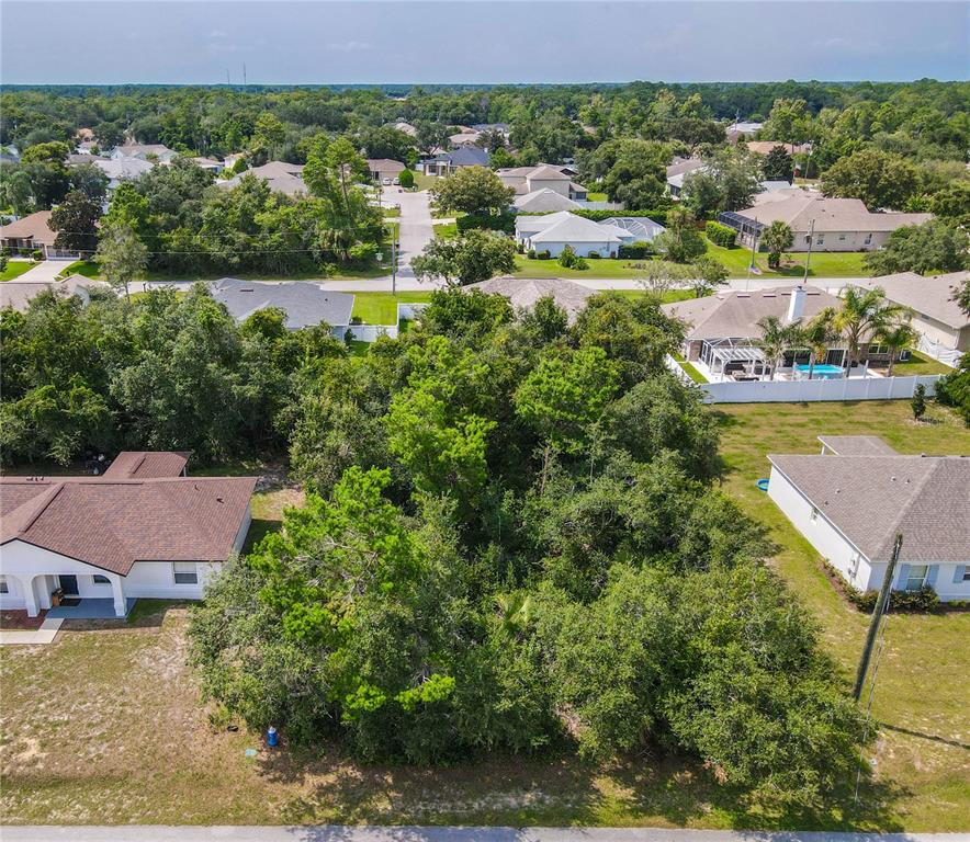 An aerial view shows a wooded lot situated between two residential houses in a neighborhood — 76 FREEPORT LANE, PALM COAST, FL