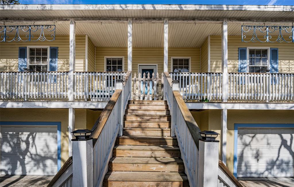 A wooden porch with yellow siding, white rocking chairs, and a white door — 5127 BAY BOULEVARD, PORT RICHEY, FL