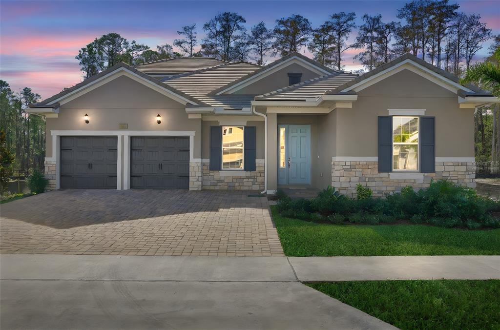 A single-story house with a two-car garage, stone accents, and a light blue front door — 14353 CREST PALM AVENUE, WINDERMERE, FL