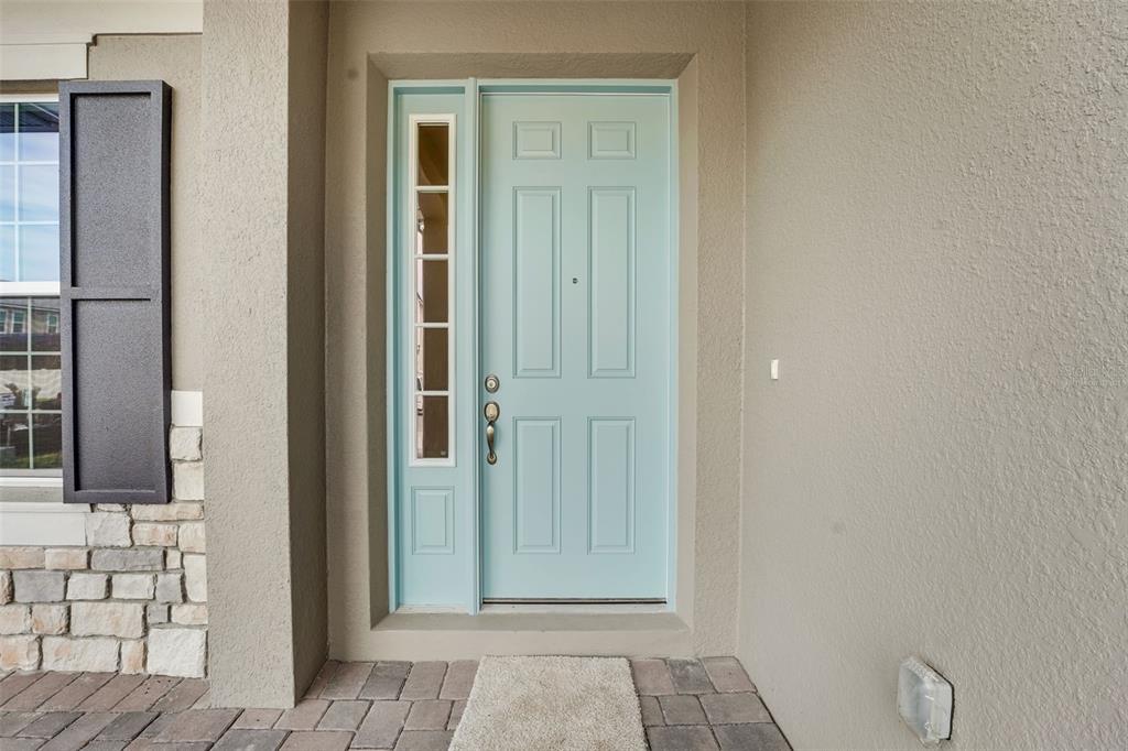 A light blue front door with a side window sits under a covered entryway — 14353 CREST PALM AVENUE, WINDERMERE, FL