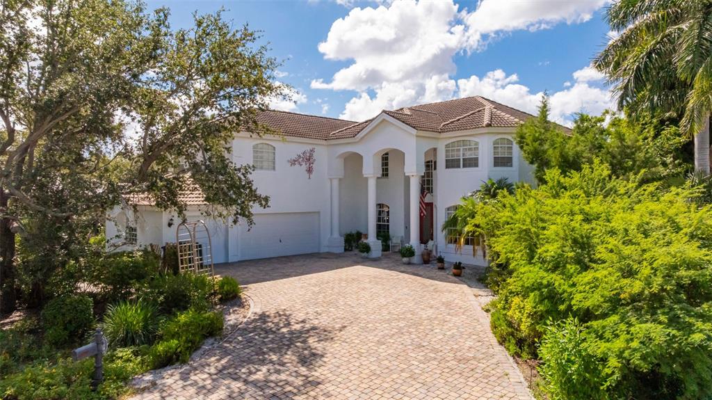 A two-story white house with a paved driveway and a large tree in the front — 13881 BLENHEIM TRAIL ROAD, FORT MYERS, FL