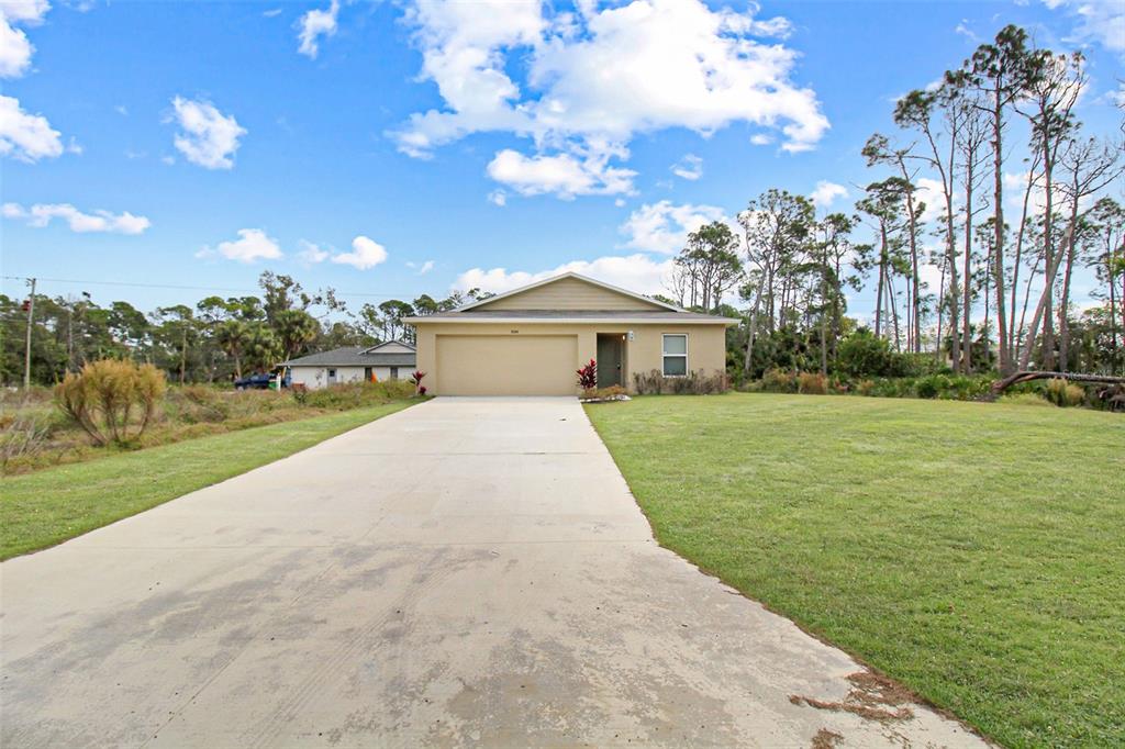 A single-story house with a beige exterior, a two-car garage, and a concrete driveway — 3084 SUDBURY STREET, PORT CHARLOTTE, FL