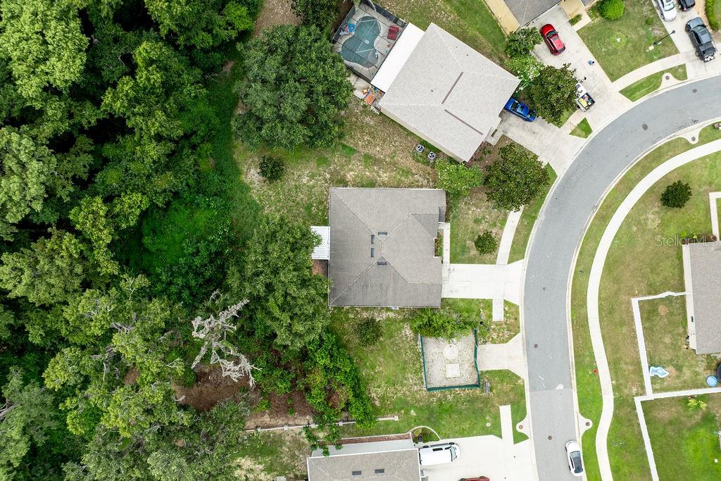 An aerial view shows a residential house with a gray roof surrounded by trees — 7830 SLOEWOOD DRIVE, LEESBURG, FL