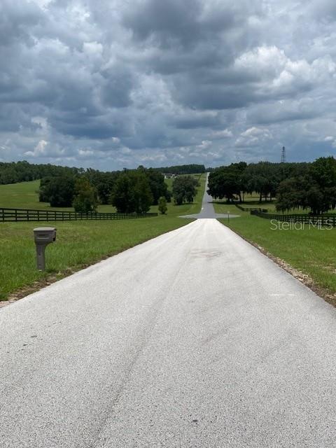 A paved driveway stretches through a grassy field toward a distant tree line — 5610 EAST ORION CT, FLORAL CITY, FL
