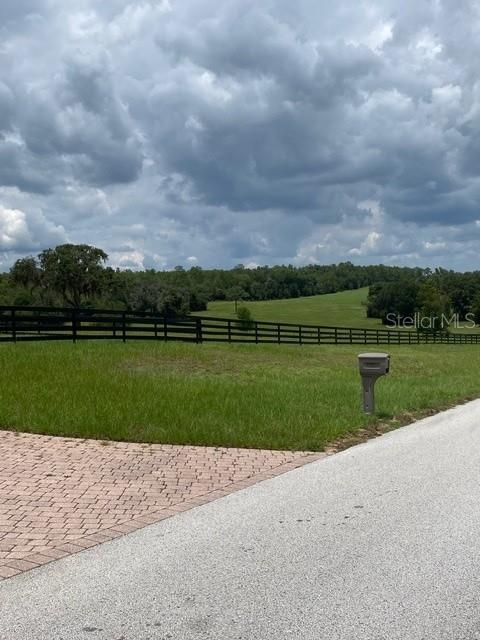 A paved driveway leads to a grassy lot enclosed by a black wooden fence — 5610 EAST ORION CT, FLORAL CITY, FL