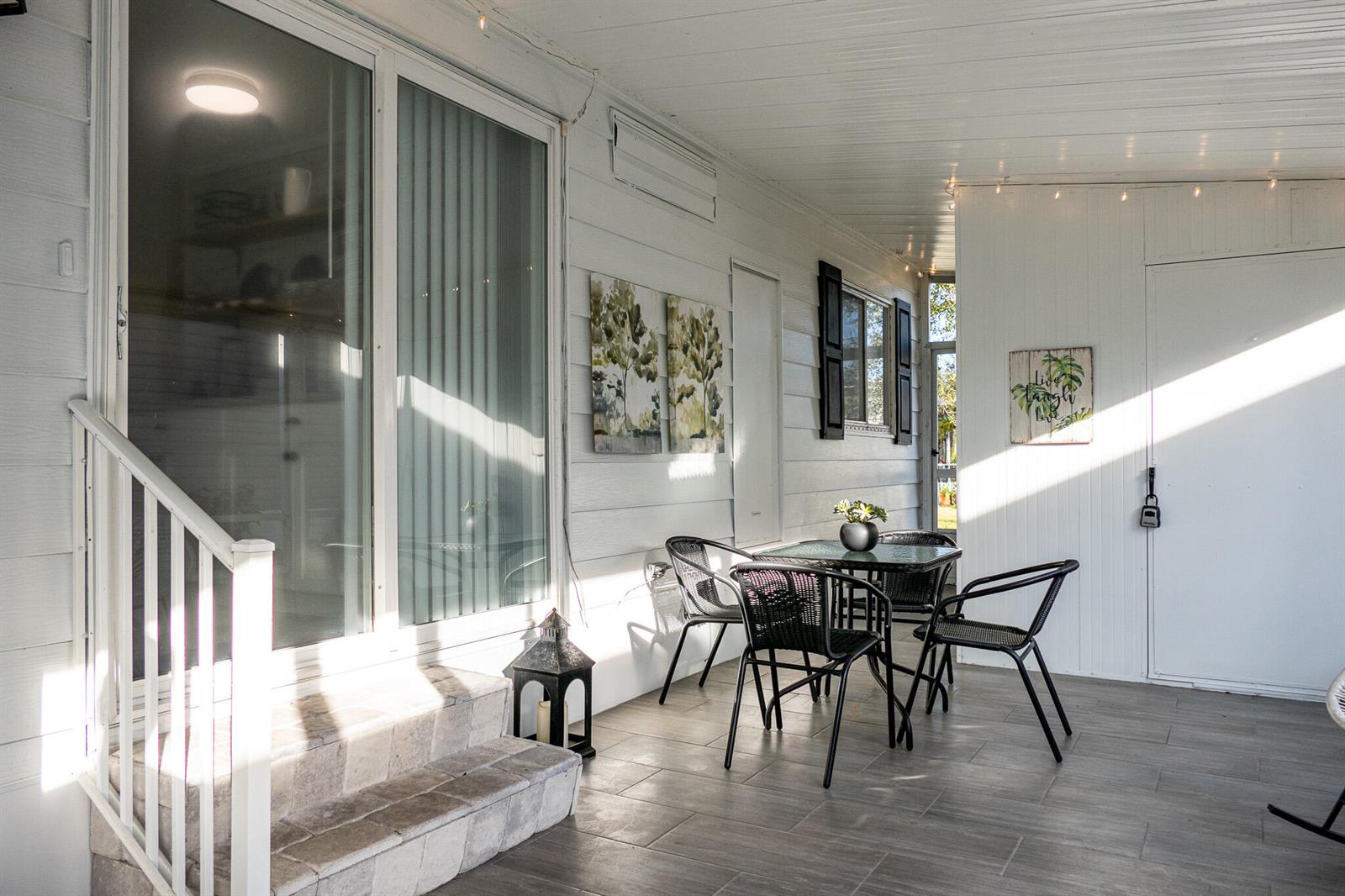 A covered patio features tiled flooring, a small dining set, and a sliding glass door — 95 N North Warner Drive, Jensen Beach FL 34957, JENSEN BEACH, FL