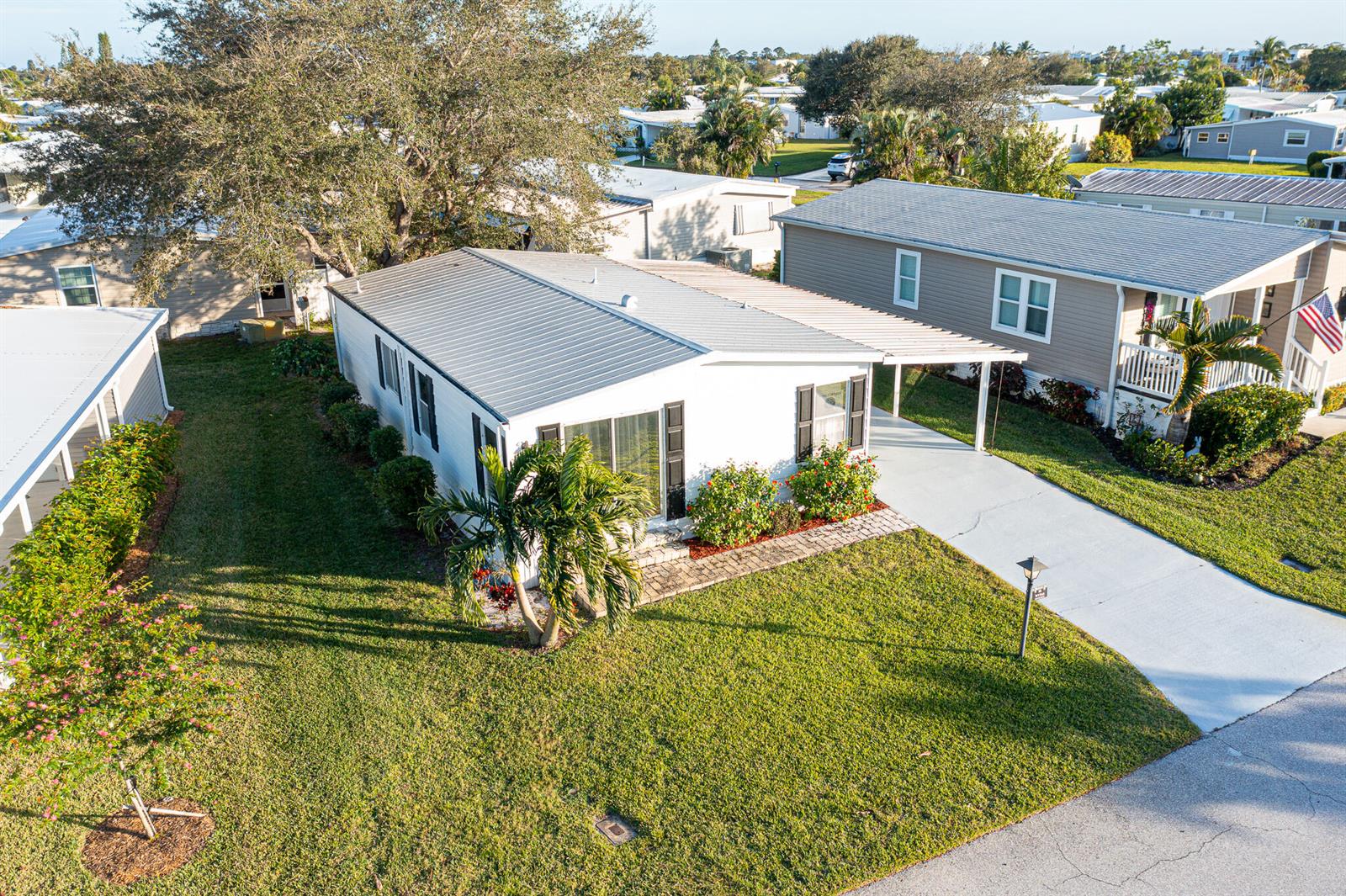 An aerial view shows a white mobile home with a metal roof and concrete driveway — 95 N North Warner Drive, Jensen Beach FL 34957, JENSEN BEACH, FL