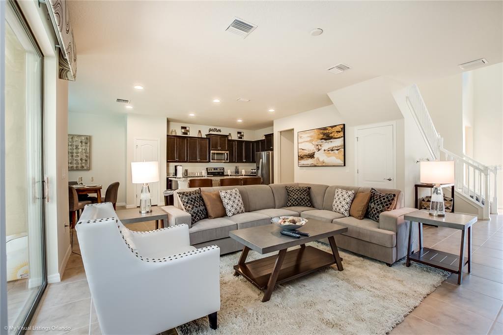 A living room with a sectional sofa, white armchair, and an open kitchen in back — 1857 NICE COURT, KISSIMMEE, FL