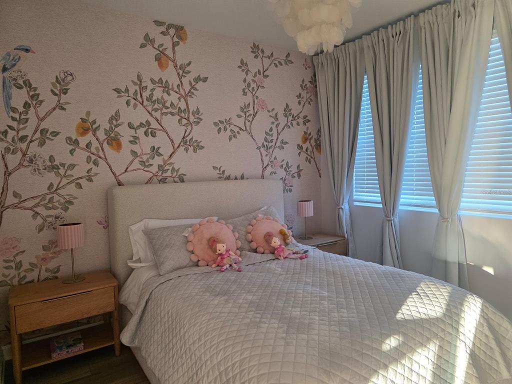 A bedroom features a floral wallpaper accent wall, a light-colored bed, and floor-length curtains — 1213 REUNION VILLAGE BOULEVARD, REUNION, FL