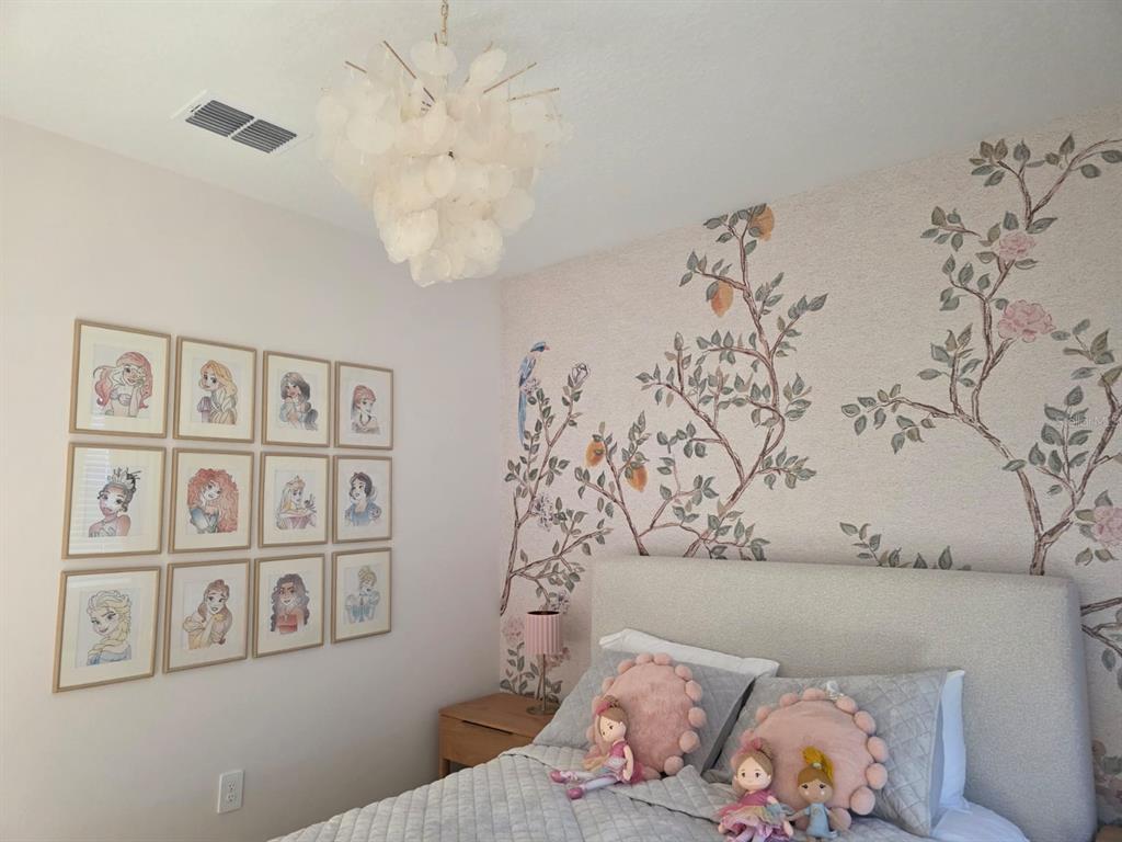 A bedroom features a floral mural, a grid of framed princess art, and a chandelier — 1213 REUNION VILLAGE BOULEVARD, REUNION, FL