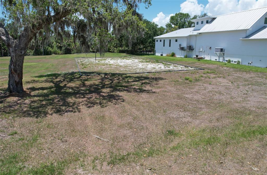A large, white house stands next to a fenced-in, sandy rectangular area in a yard — 8325 ALAFIA POINTE DRIVE, RIVERVIEW, FL