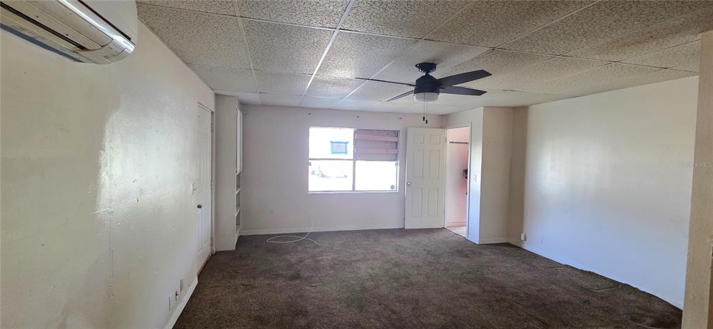 An empty room features brown carpeting, a ceiling fan, a window, and a wall-mounted air conditioner — 205 DIXIE HIGHWAY, AUBURNDALE, FL