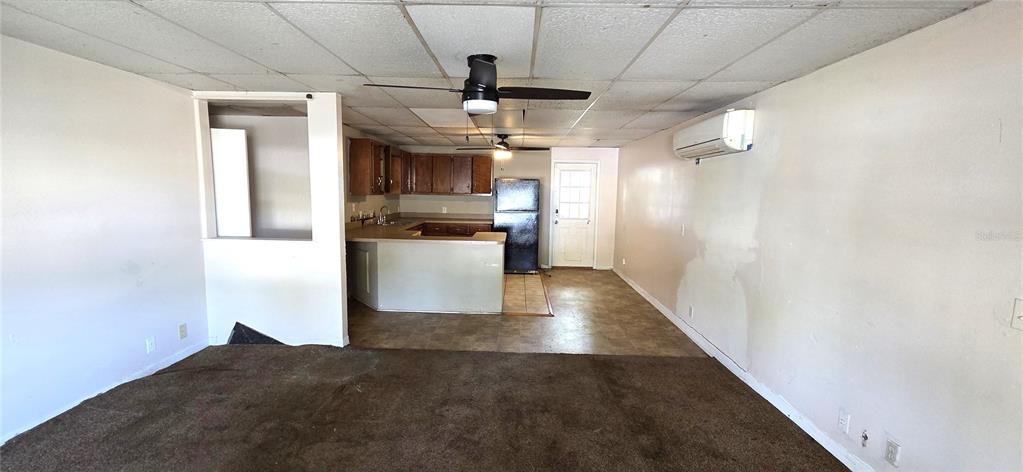 A living room with brown carpet leads to a kitchen featuring wood cabinets and appliances — 205 DIXIE HIGHWAY, AUBURNDALE, FL