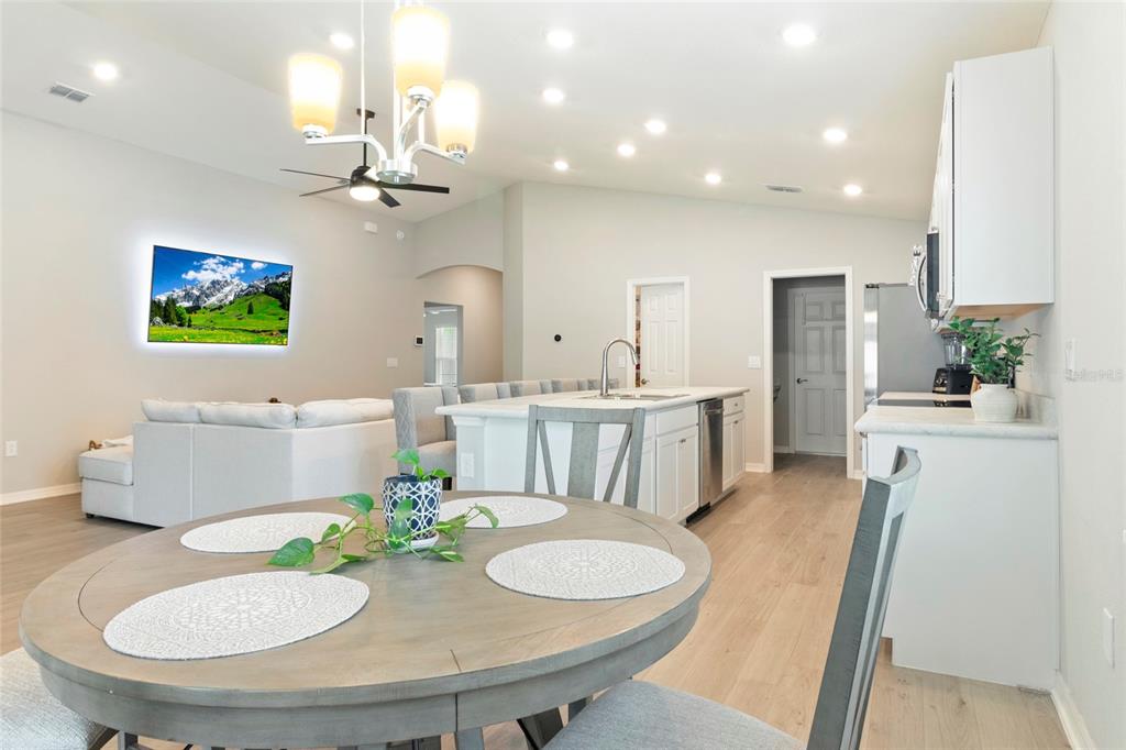 A bright open-concept kitchen and living area featuring a central island and dining table — 1204 MEZZAVALLE WAY, AUBURNDALE, FL