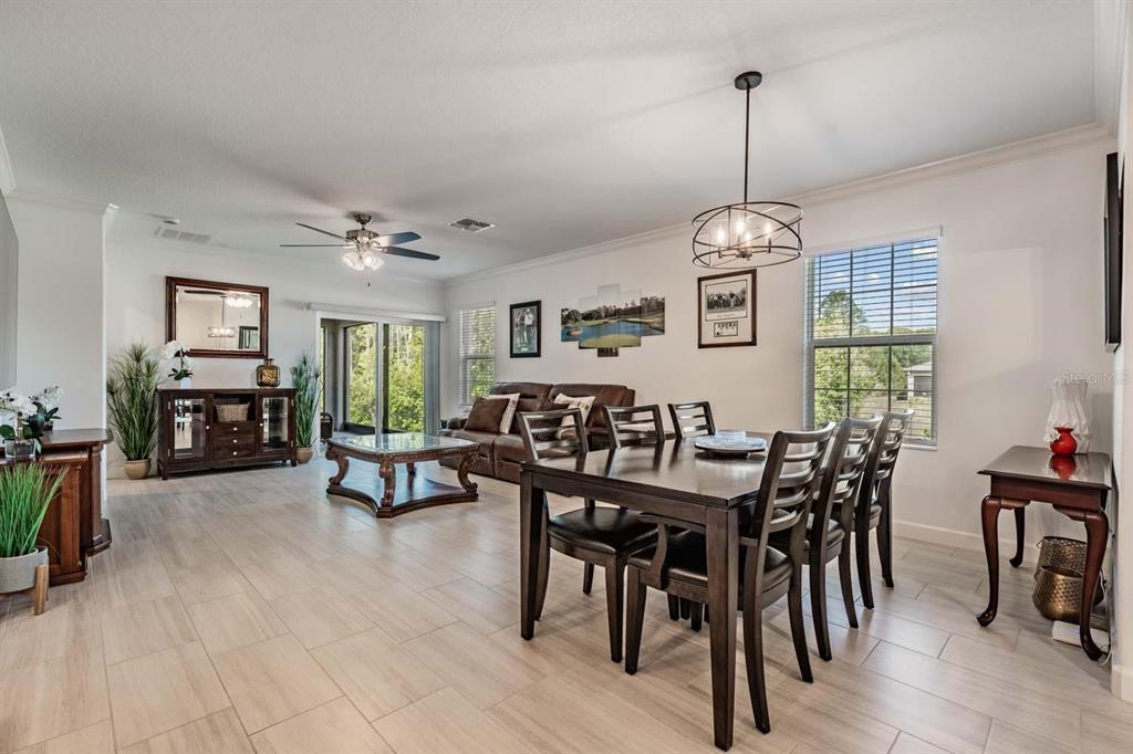 A dining area and living room with tile flooring, dark wood furniture, and a ceiling fan — 16595 SHELL BAY DRIVE, LAND O LAKES, FL