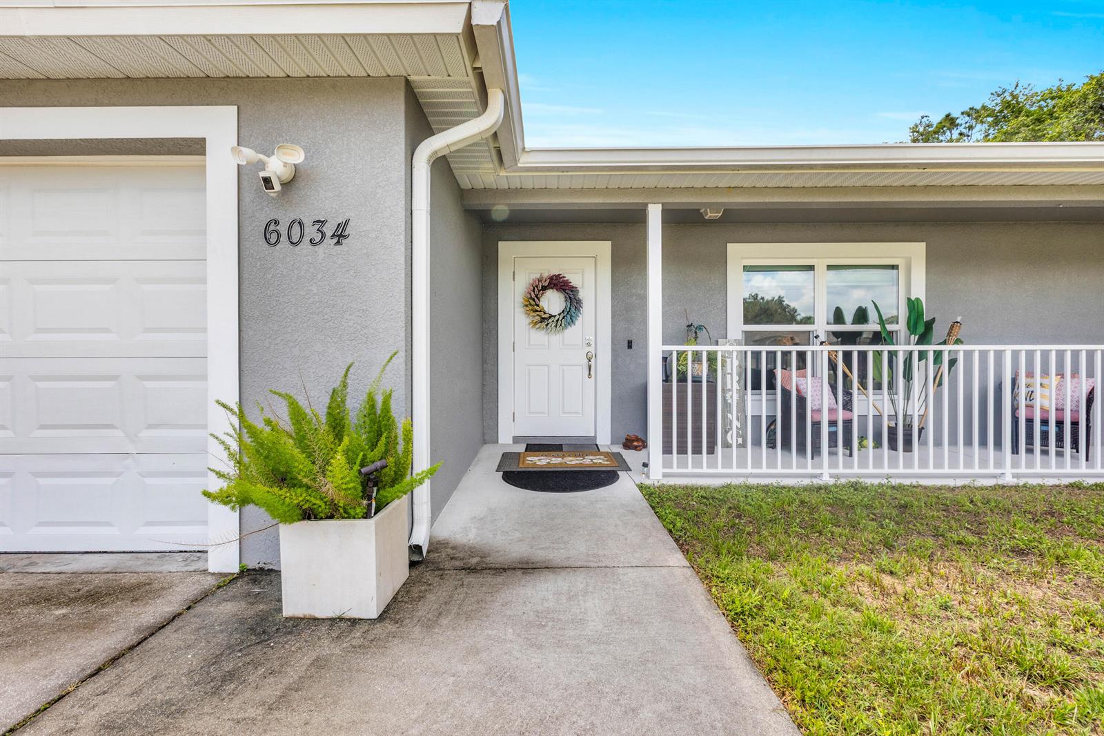 A gray house exterior features a white front door, a concrete walkway, and a porch — 6034 Twig Court, FL 33935, FL
