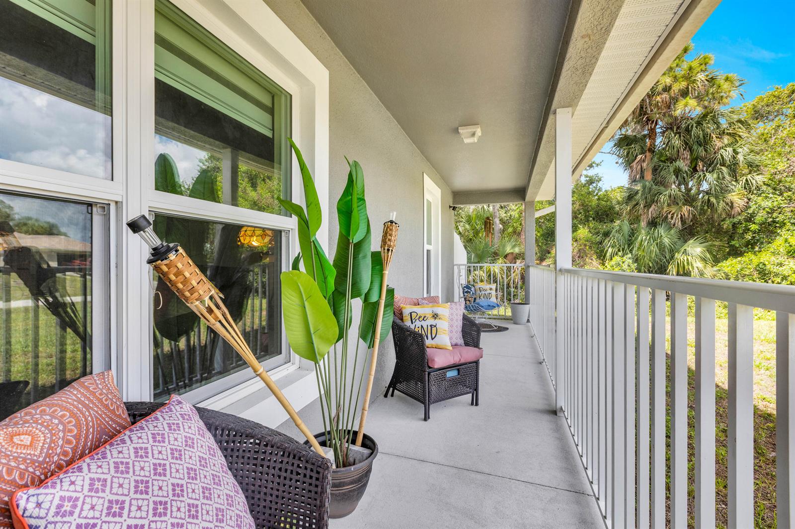 A covered outdoor balcony features wicker chairs, potted plants, and a white metal railing — 6034 Twig Court, FL 33935, FL