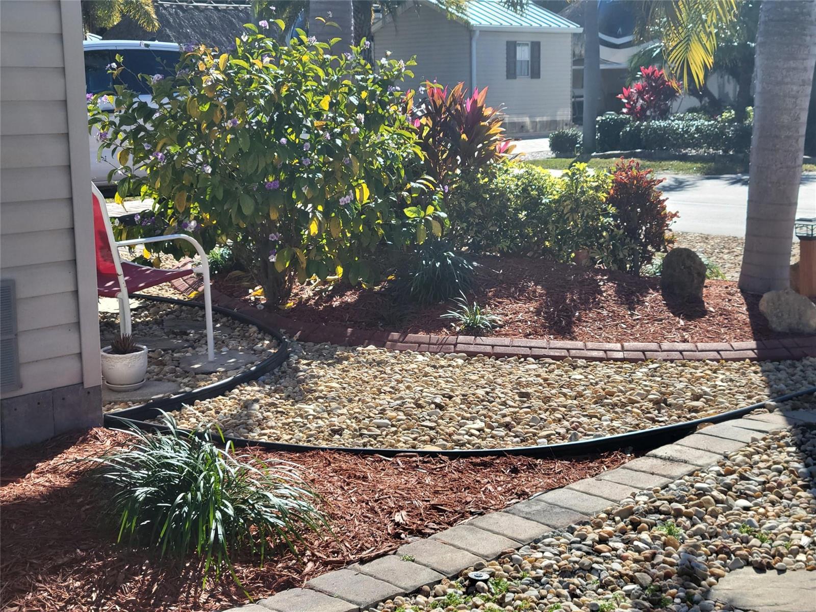 A landscaped front yard features a gravel bed, mulch, decorative stone edging, and various shrubs — 551 SW 42nd Cove, Okeechobee FL 34974, OKEECHOBEE, FL