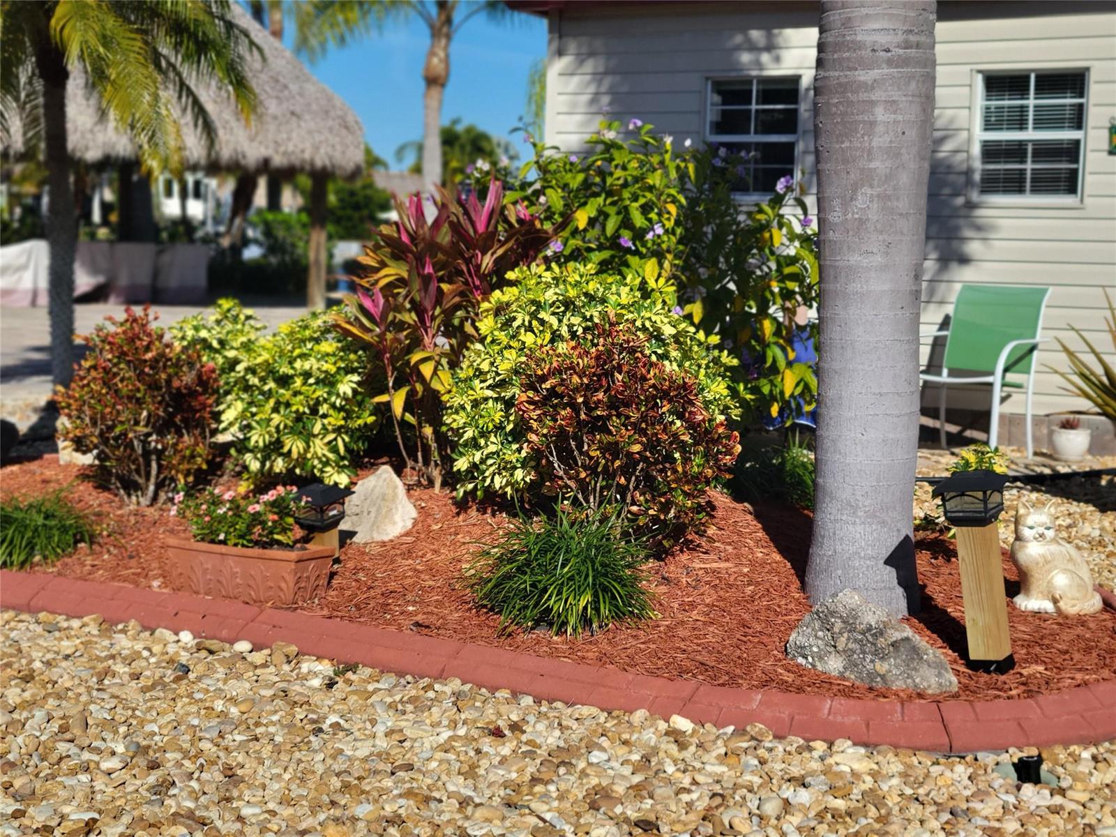 A landscaped garden bed with mulch, shrubs, and a palm tree in front of a house — 551 SW 42nd Cove, Okeechobee FL 34974, OKEECHOBEE, FL