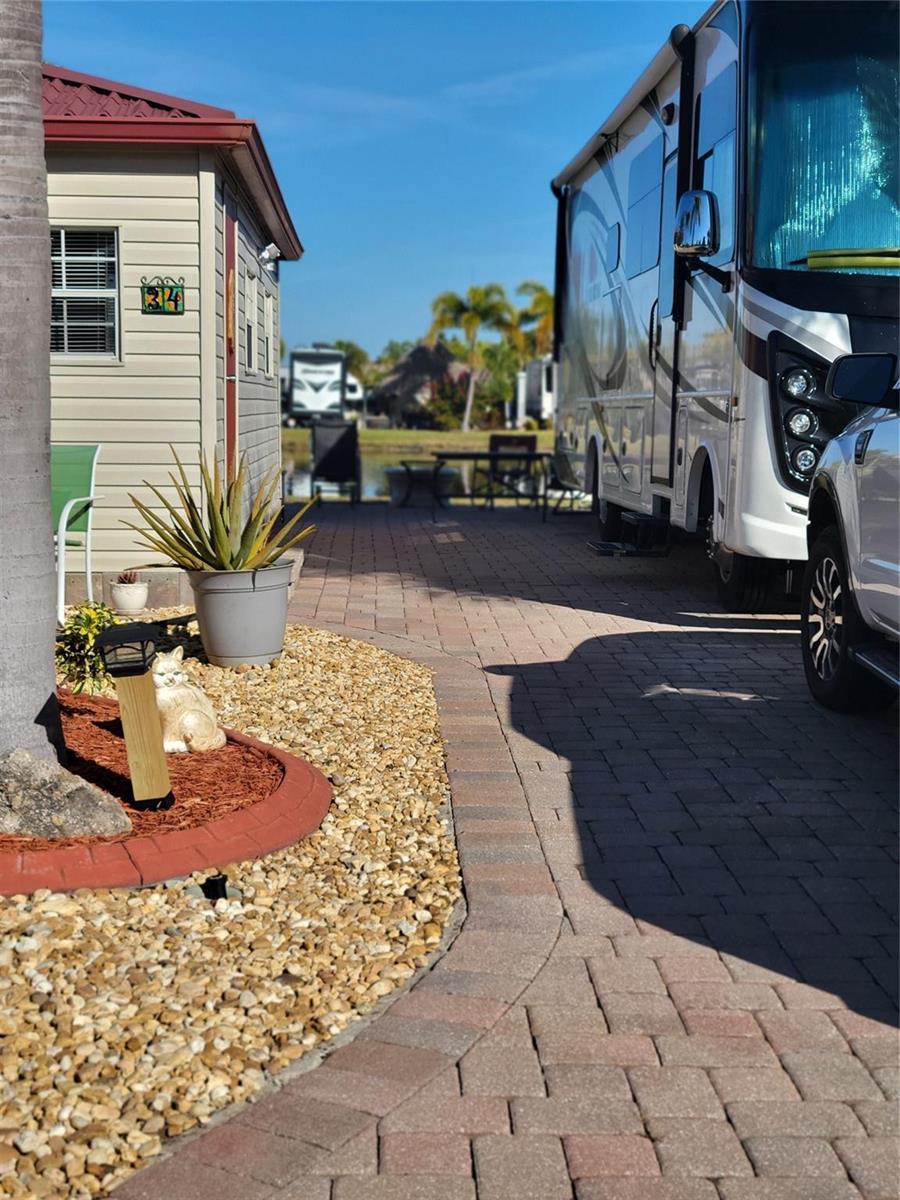 A paved driveway sits between a small house and a large recreational vehicle — 551 SW 42nd Cove, Okeechobee FL 34974, OKEECHOBEE, FL