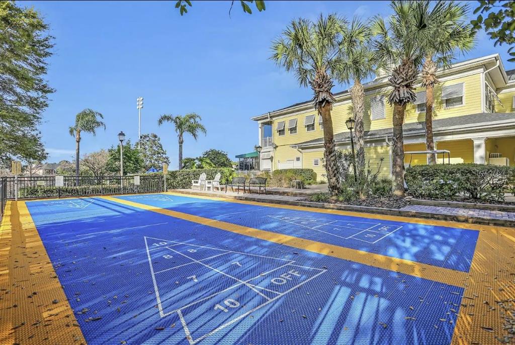 An outdoor shuffleboard court with blue and yellow tiles sits beside a yellow building — 706 GRAN BAHAMA BOULEVARD UNIT 706, DAVENPORT, FL