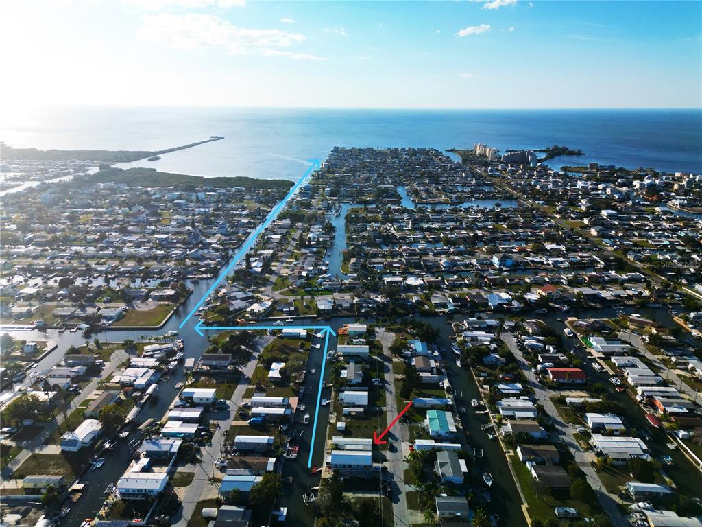 An aerial view shows a residential neighborhood with canals leading to the open water — 6814 GULL LANE, HUDSON, FL
