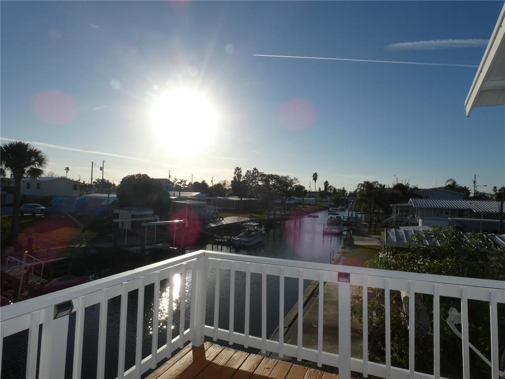 A view from a wooden deck overlooking a canal with boats and residential homes — 6814 GULL LANE, HUDSON, FL