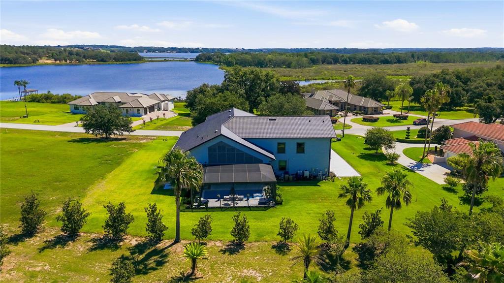 An aerial view shows a large house with a screened pool deck near a lake — 17025 ROYAL PALM DRIVE, GROVELAND, FL