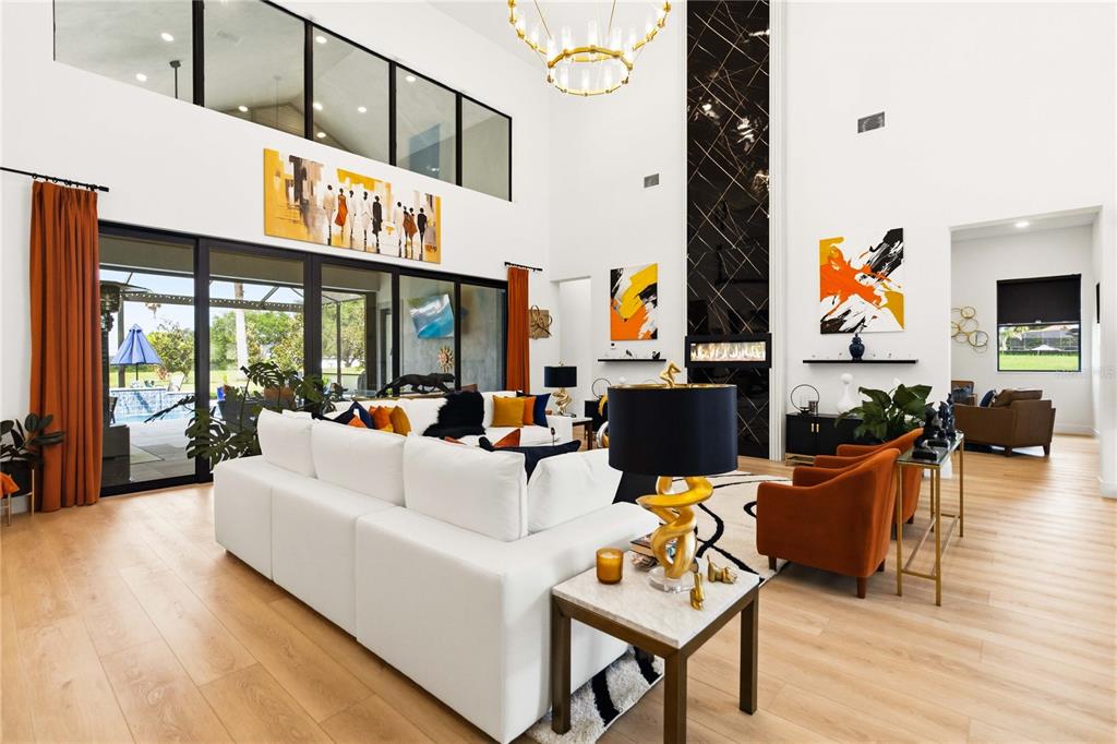 A spacious living room features high ceilings, a large white sectional, and a black fireplace — 17025 ROYAL PALM DRIVE, GROVELAND, FL
