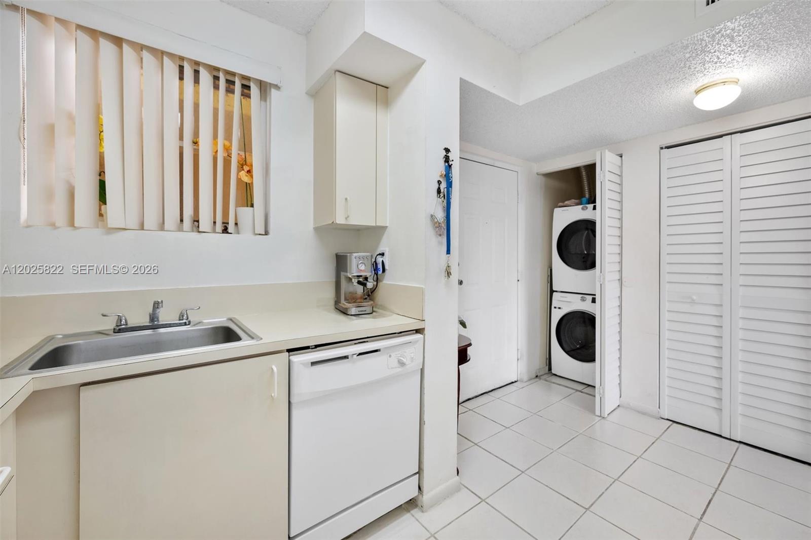 A kitchen area features a sink, dishwasher, and a stacked washer and dryer unit — 14951 SW 82nd Ln # 403, Miami FL 33193, MIAMI, FL