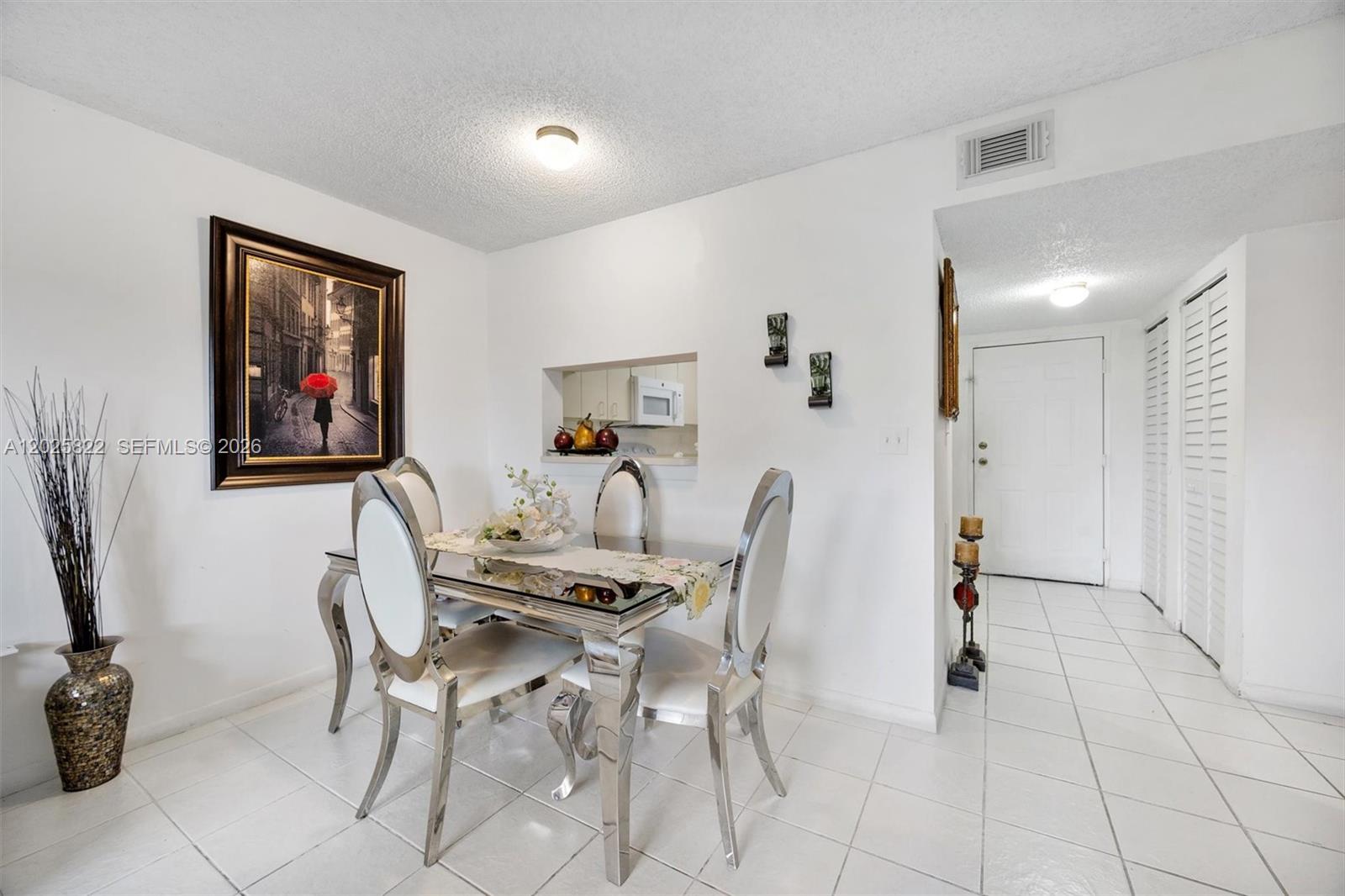 A dining area features a glass-topped table, four silver chairs, and white tile flooring — 14951 SW 82nd Ln # 403, Miami FL 33193, MIAMI, FL