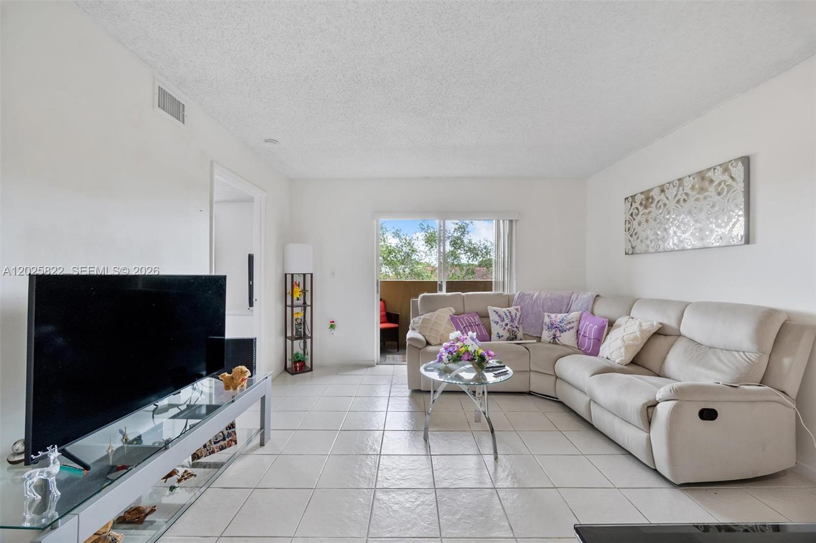 A living room features a white sectional sofa, a glass coffee table, and tile flooring — 14951 SW 82nd Ln # 403, Miami FL 33193, MIAMI, FL