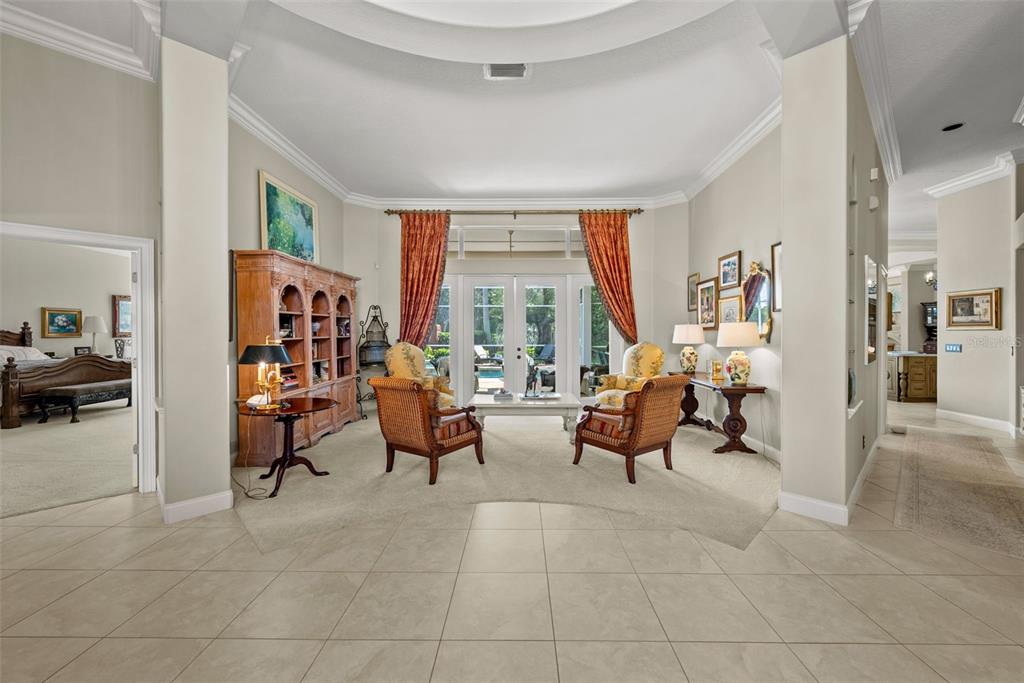 A formal living room features a large wooden bookcase, four armchairs, and glass patio doors — 6453 RENWICK CIRCLE, TAMPA, FL