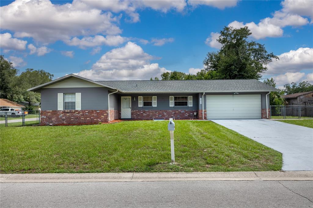 A single-story house with a gray exterior, brick base, and an attached two-car garage — 1868 NE 29TH STREET, OCALA, FL