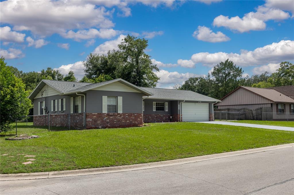 A single-story house with gray siding, a brick base, and an attached two-car garage — 1868 NE 29TH STREET, OCALA, FL