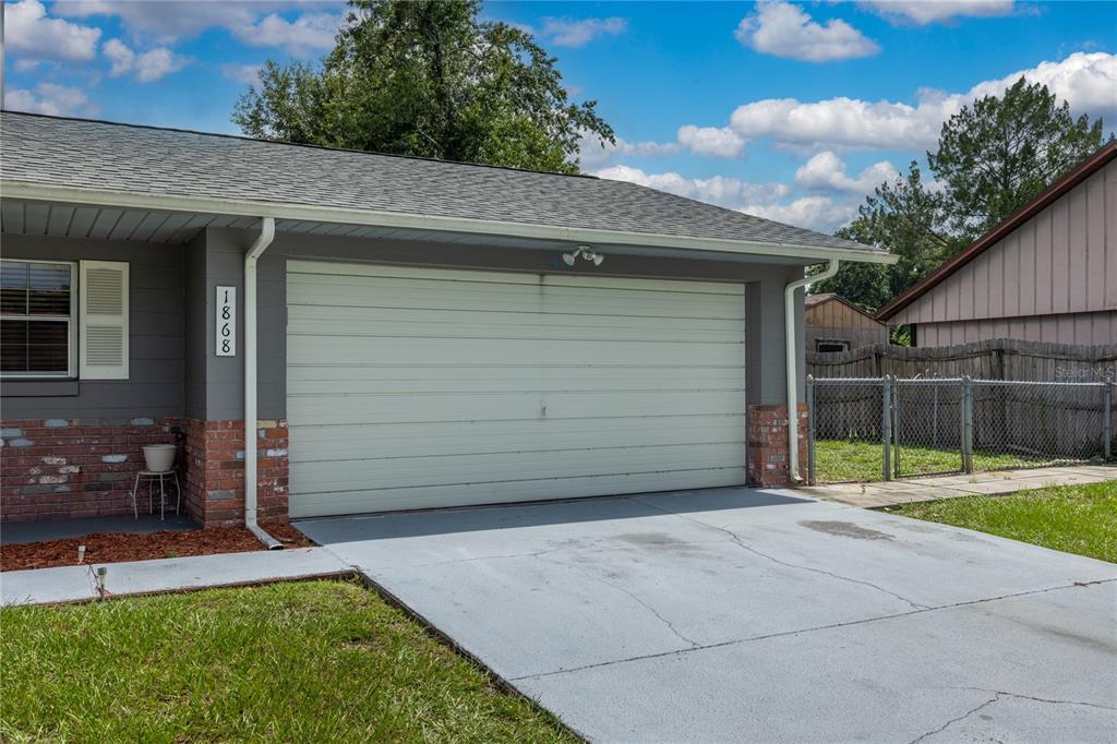 A gray house exterior features a two-car garage, brick accents, and a concrete driveway — 1868 NE 29TH STREET, OCALA, FL