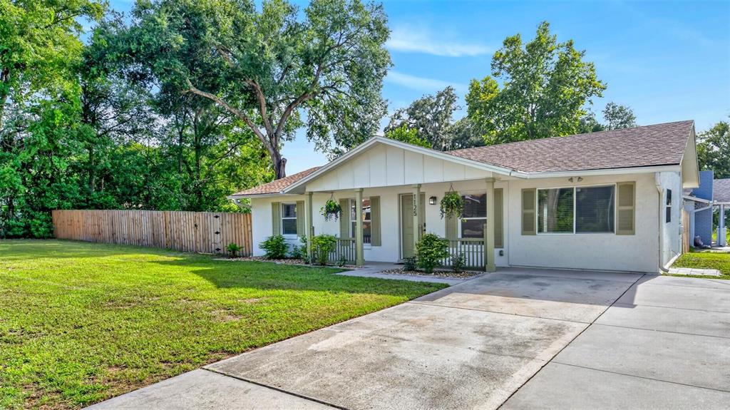 A single-story house with a concrete driveway, a front porch, and a wooden fence — 1125 N TREMAIN STREET, MOUNT DORA, FL