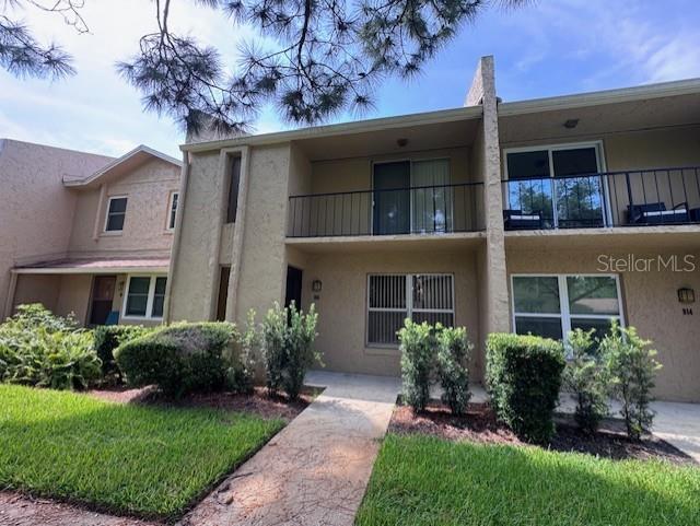 A two-story tan stucco townhouse features a second-floor balcony and a front walkway — 916 PARK LAKE CIRCLE UNIT 34, MAITLAND, FL
