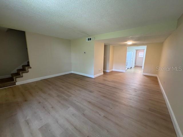 An open-concept living area features light wood-look flooring, beige walls, and a staircase — 916 PARK LAKE CIRCLE UNIT 34, MAITLAND, FL