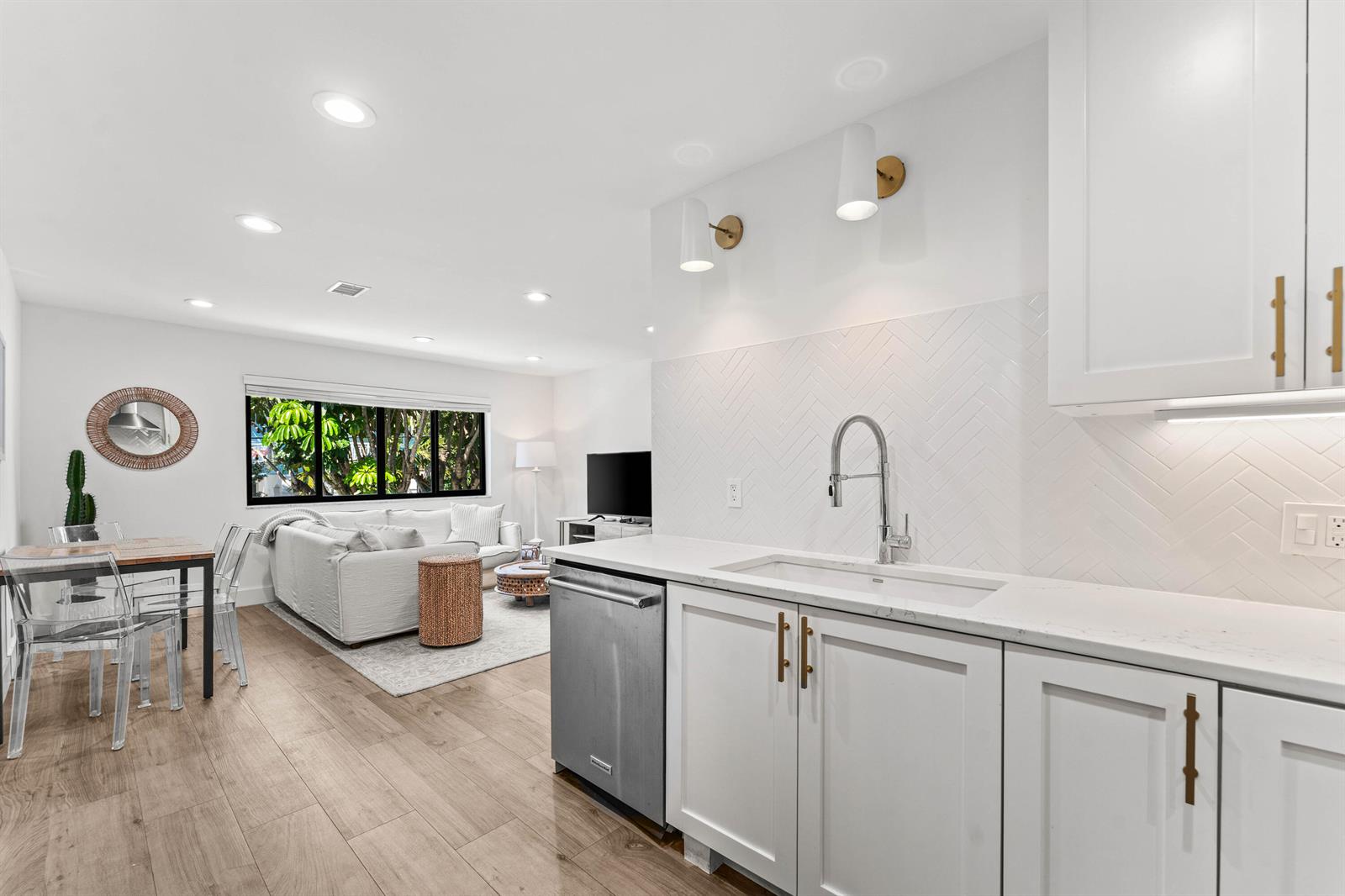 A modern kitchen with white cabinets and a herringbone backsplash opens into a living area — 250 S Ocean Boulevard # 279, Delray Beach FL 33483, DELRAY BEACH, FL