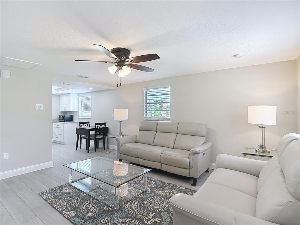 A living room with light gray tile floors, two leather sofas, and an adjacent kitchen — 14306 GUAVA STREET, HUDSON, FL