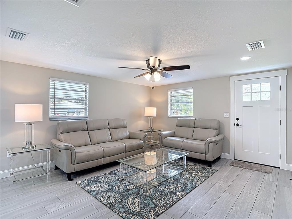 A living room features light gray leather sofas, a glass coffee table, and tile flooring — 14306 GUAVA STREET, HUDSON, FL